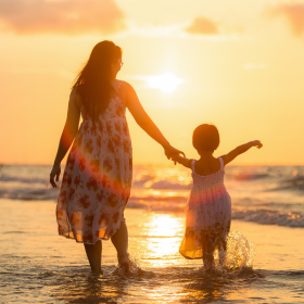 Une maman et sa fille sur la plage au coucher de soleil